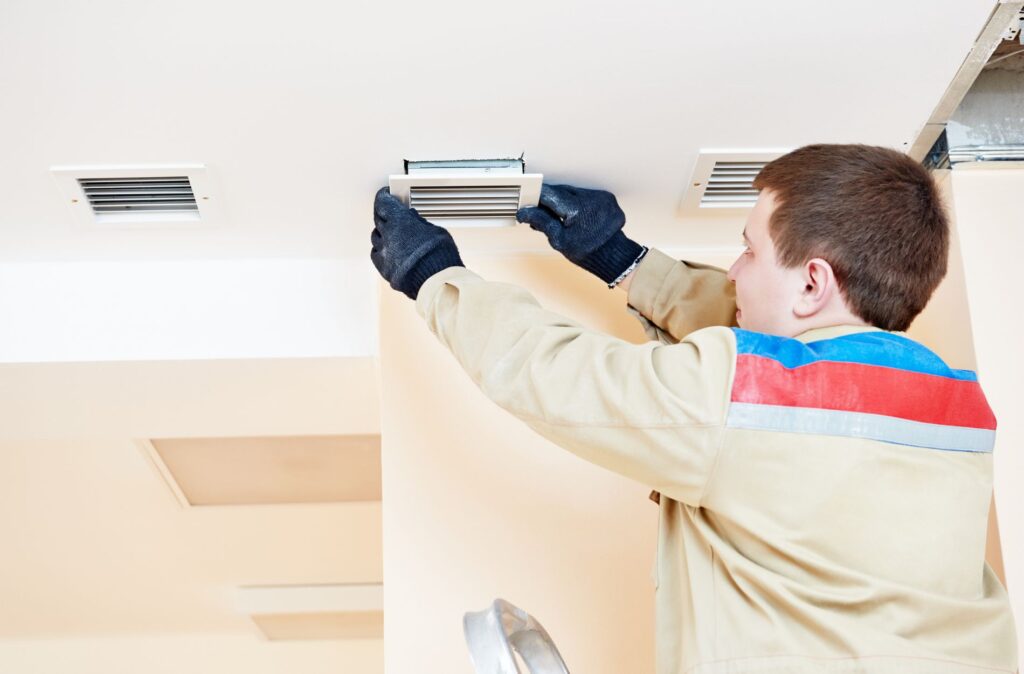 Worker installing a ceiling vent.