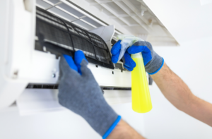 Technician cleaning an air conditioner filter with a spray bottle.